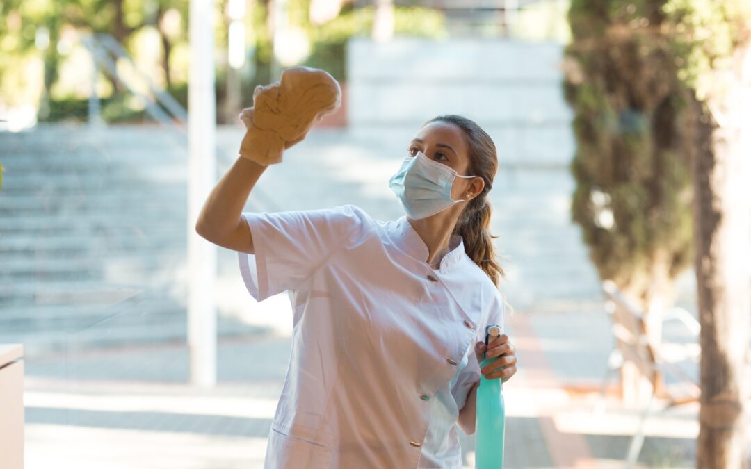 Young woman cleaning windows of clinic on outside